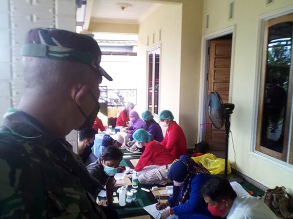 Personel Babinsa Koramil 1016-01 Pahandut Pelda Yulianto mendampingi petugas kesehatan melakukan vaksinasi secara door to door
